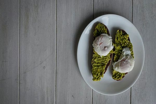 Toast de pain complet, avocat, œuf poché et graines de courge